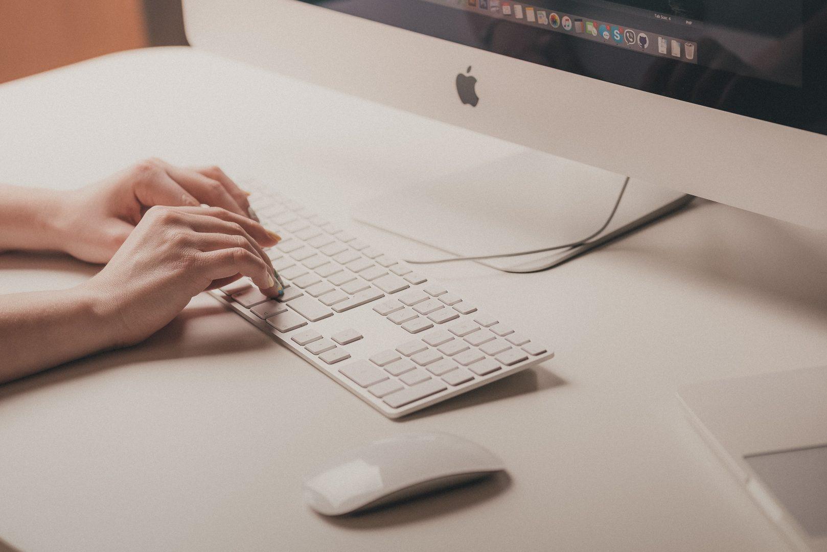 A pair of hands typing on a Mac keyboard