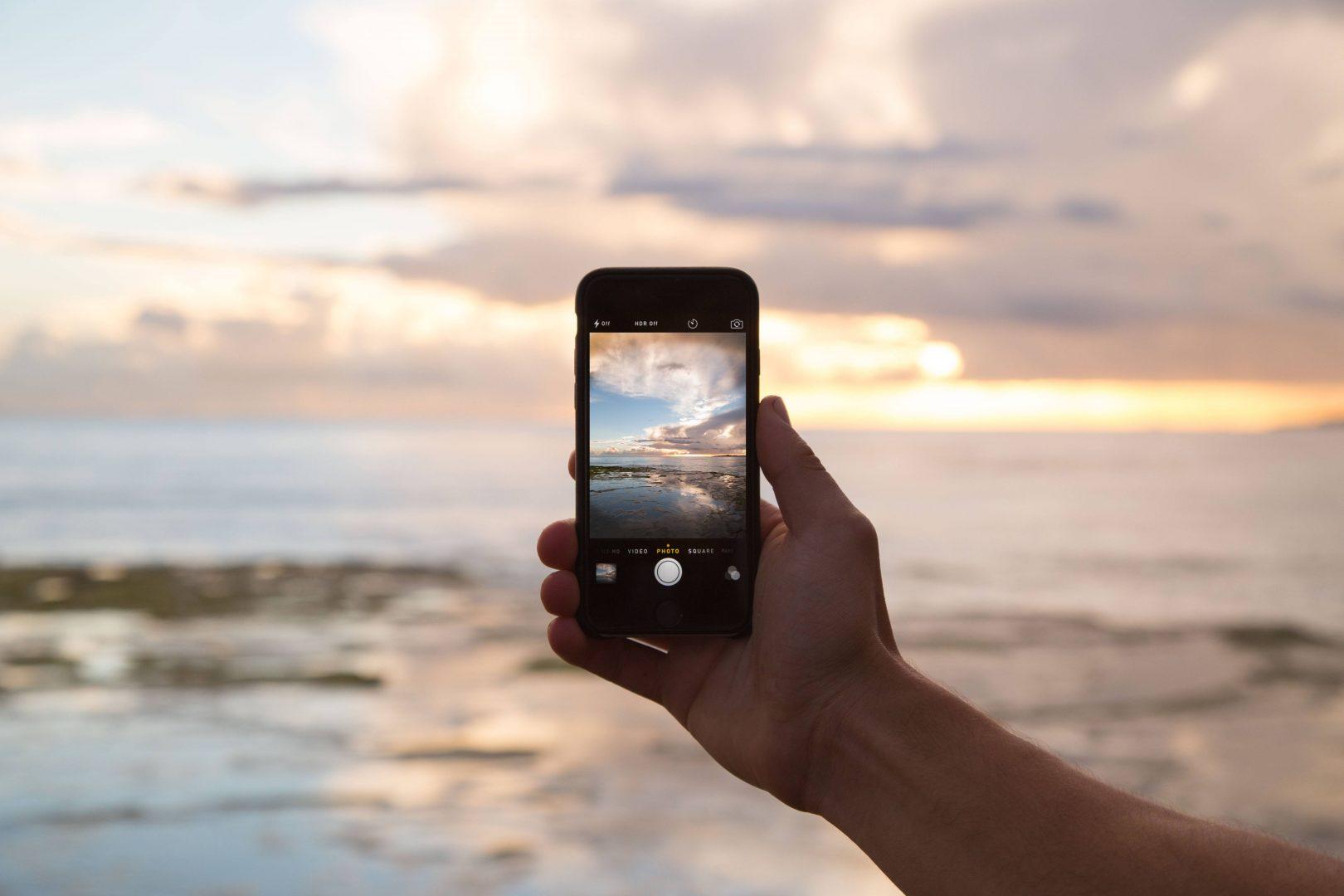 A phone being held up against a sunset | marketing Surrey