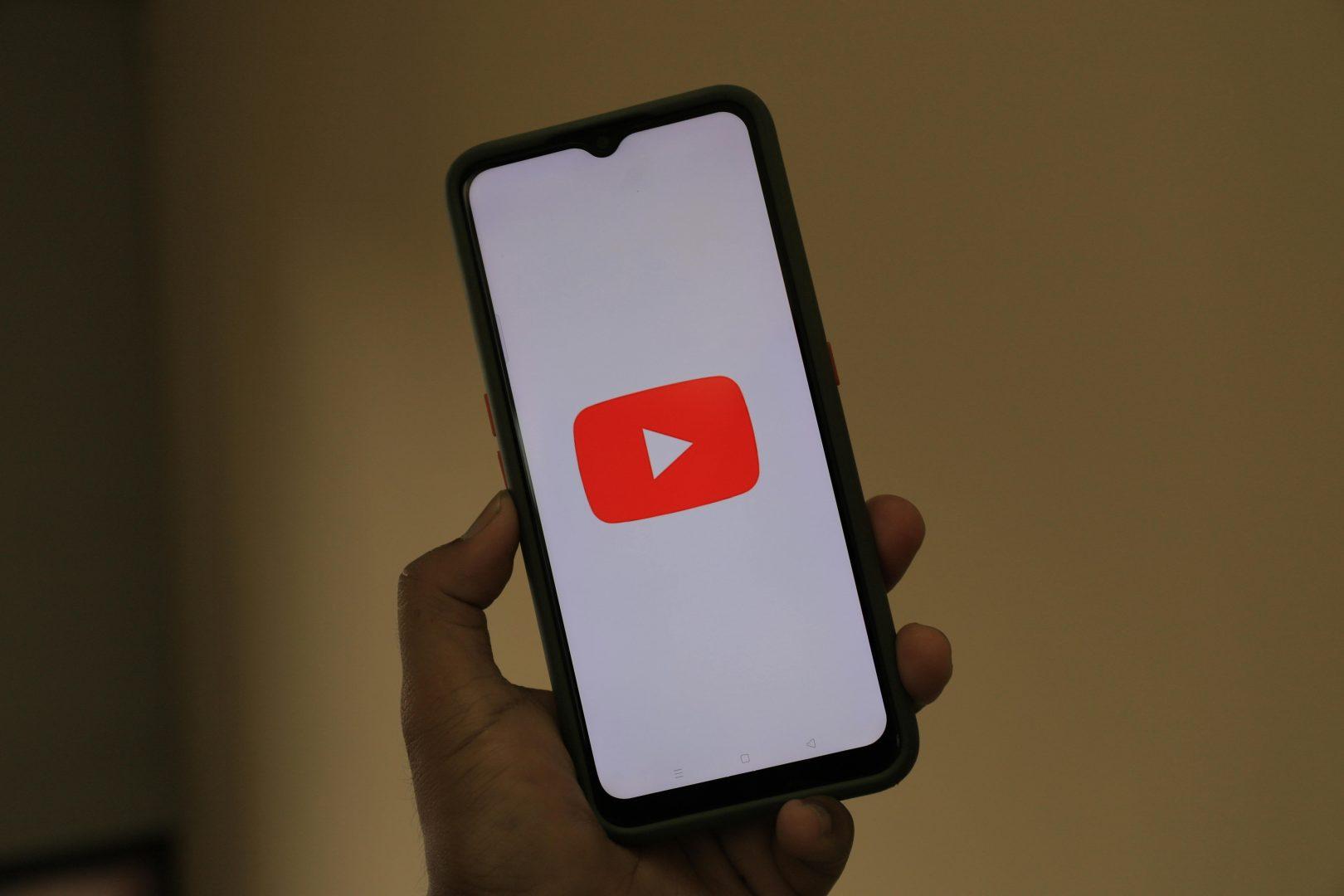 A hand holding a phone with the YouTube play button on the screen | Digital Marketing Farnham