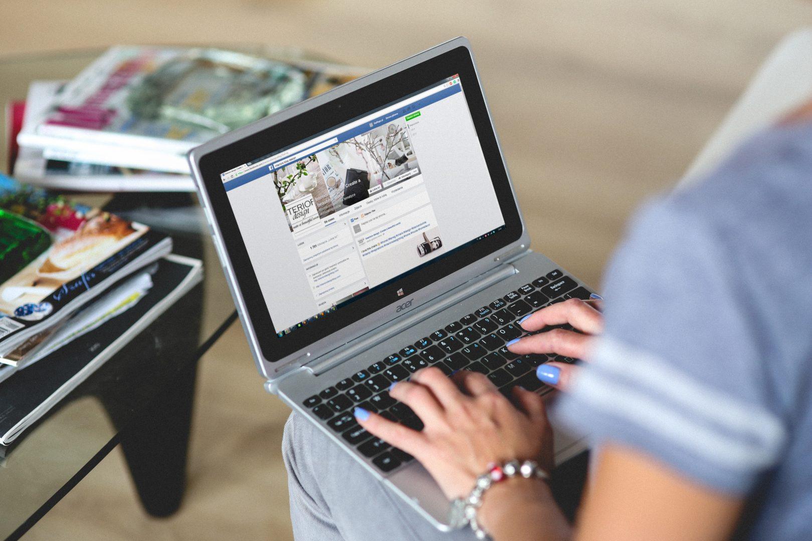 A woman looking at a Facebook business page on a laptop