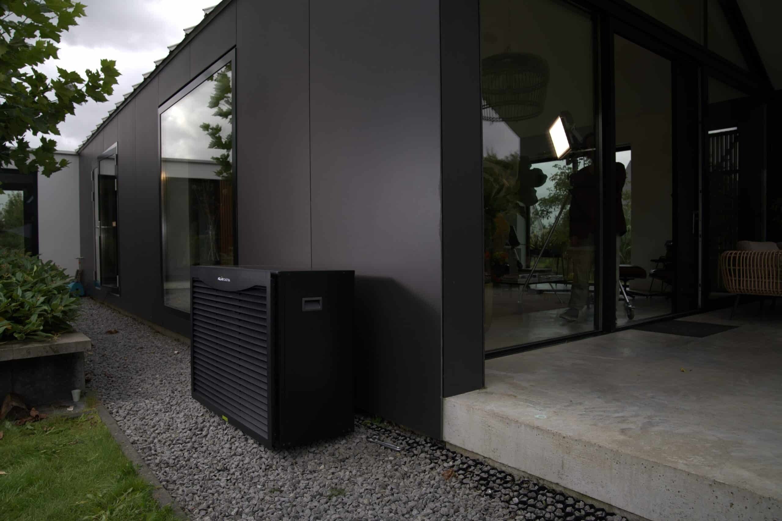 An Adlår Castra heat pump external unit placed outside of a modern home