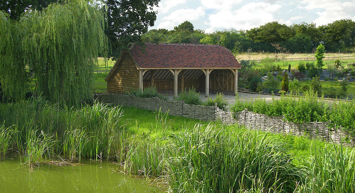 A bespoke oak barn created by The Brookwood Barn Co, nestled in green scenery | Technical SEO