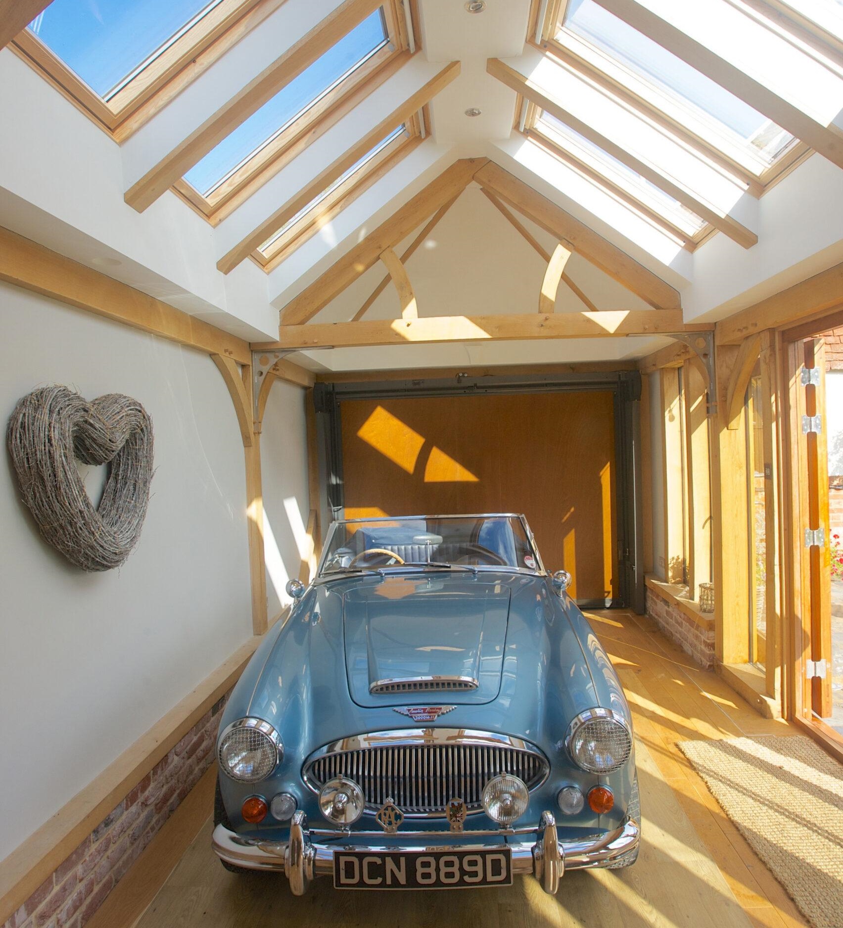 An oak-framed garage with Velux windows, housing a classic car