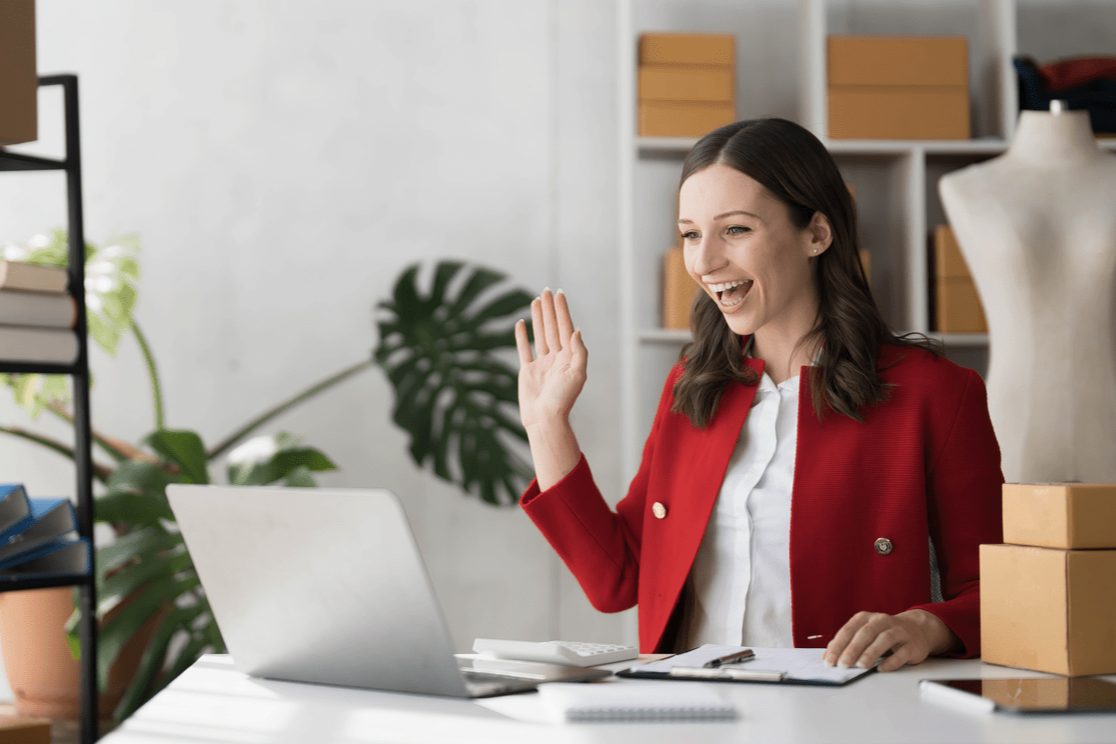 Smartly dressed woman waving to her laptop camera | Social media marketing Surrey