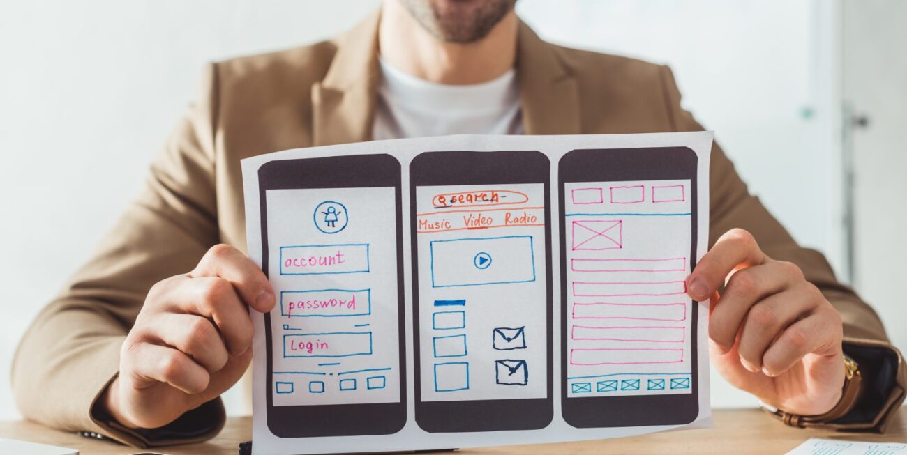 A man holding a piece of paper featuring mobile web design