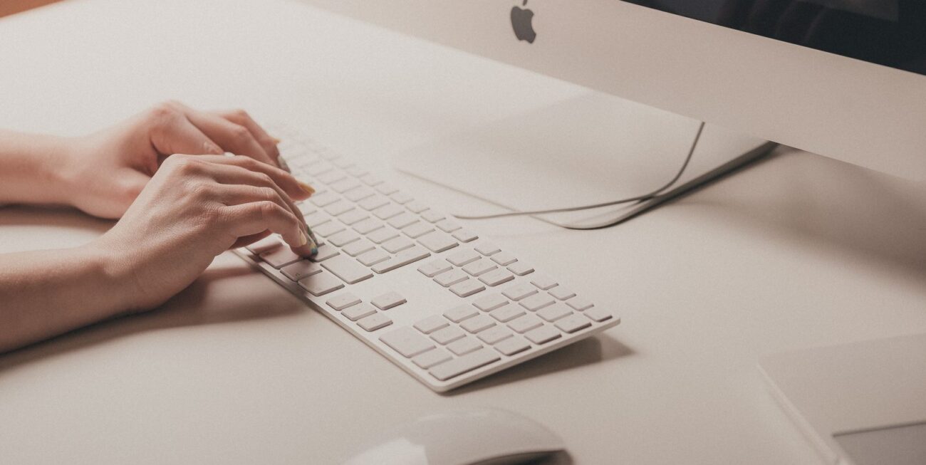A pair of hands typing on a Mac keyboard