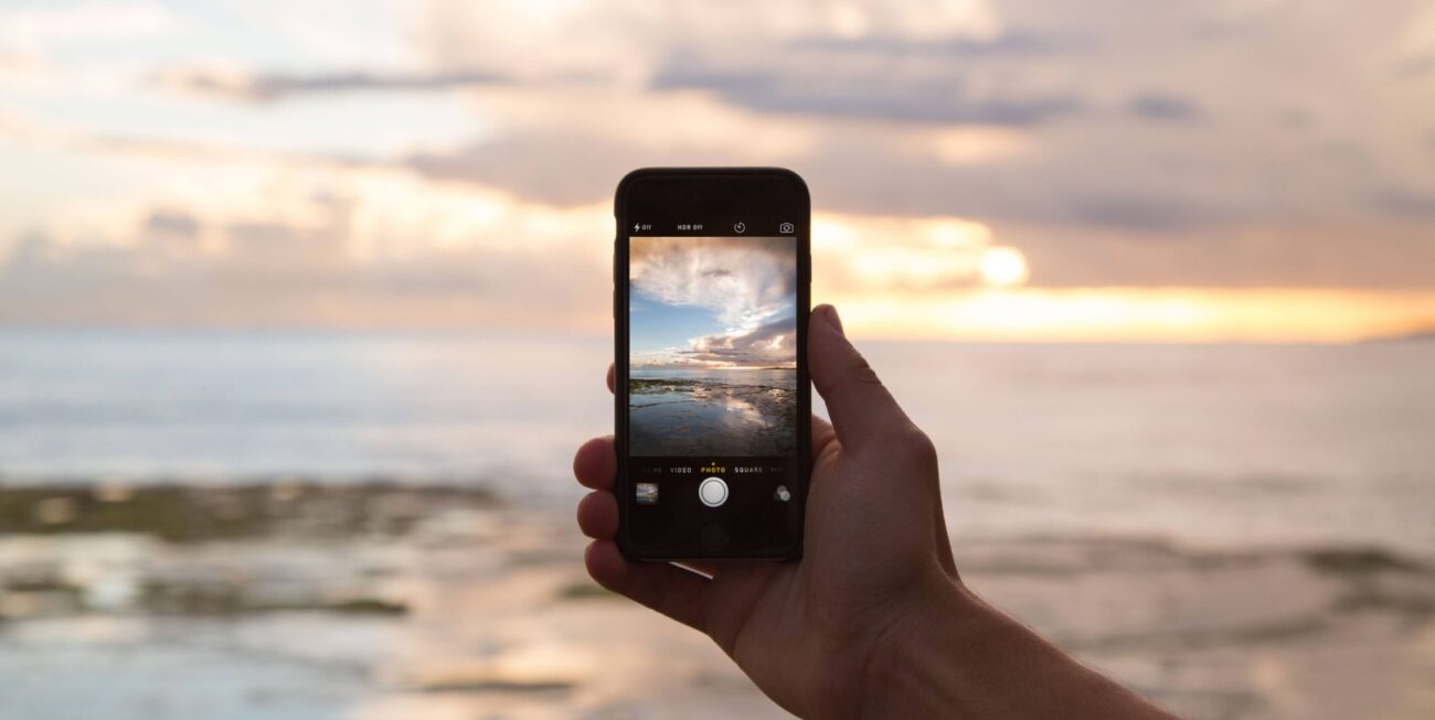 A phone being held up against a sunset | marketing Surrey