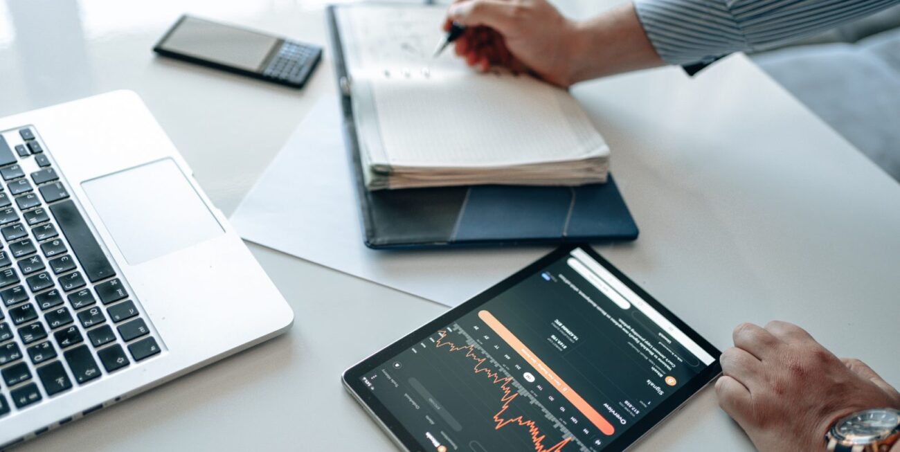 Someone working at their desk with a laptop, tablet, phone, and appointment book
