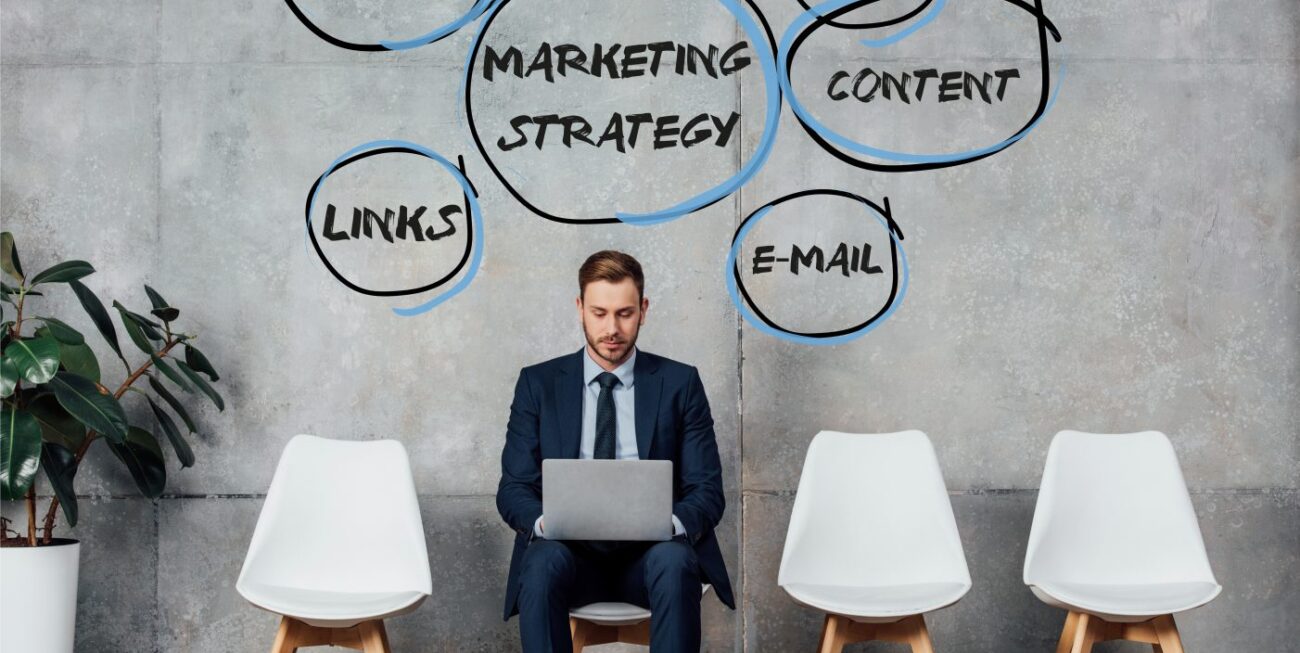smiling businessman sitting on chair and using laptop