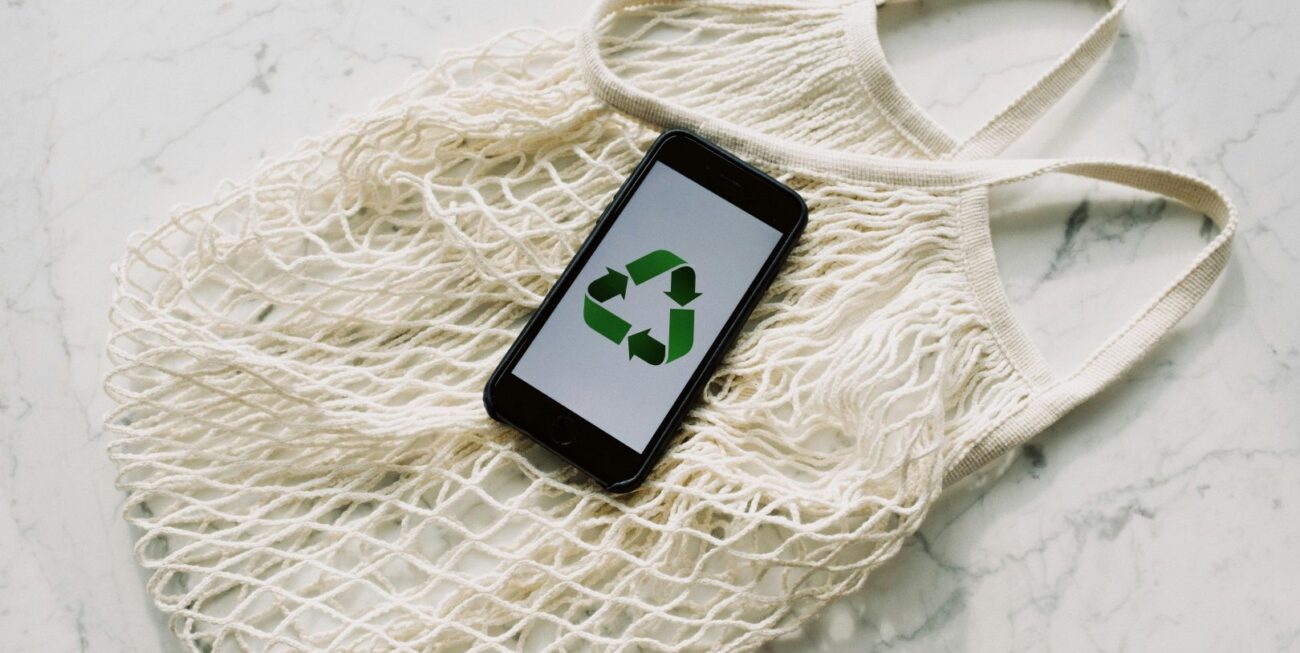 A phone displaying the recycling sign atop a reusable shopping bag | Web Designers in Surrey