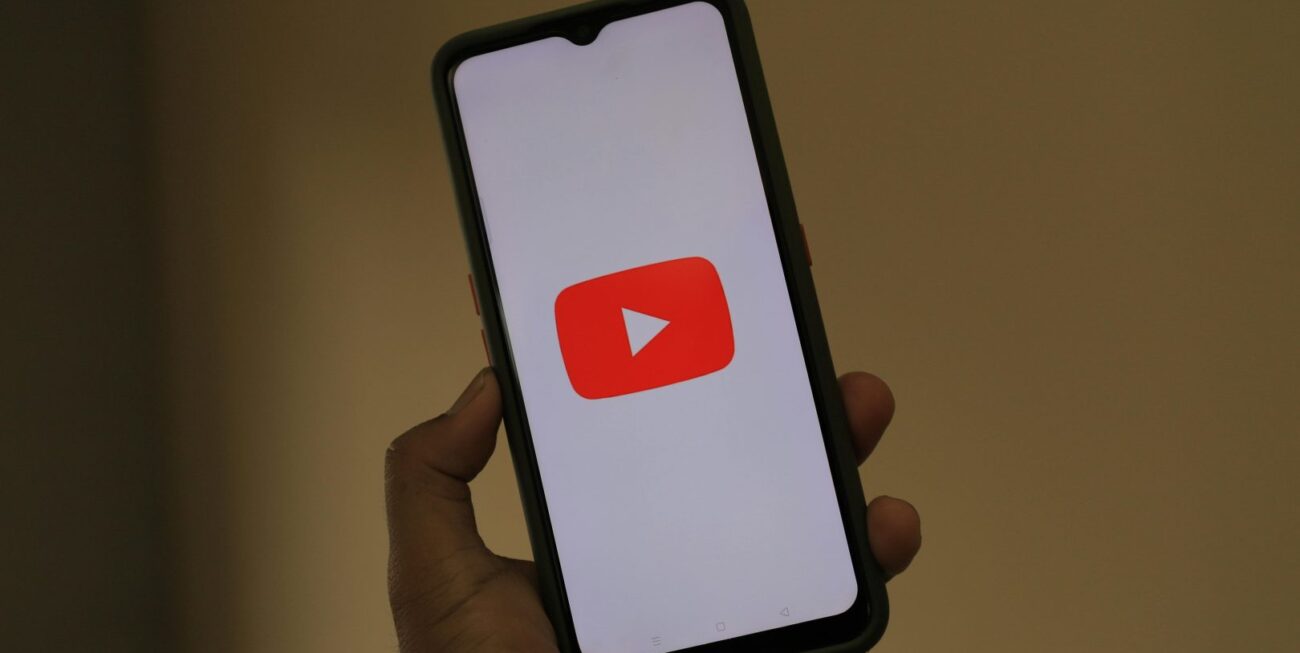 A hand holding a phone with the YouTube play button on the screen | Digital Marketing Farnham