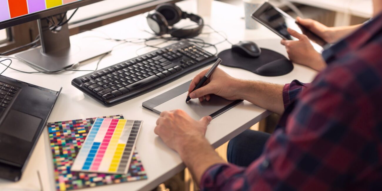 A graphic designer using a drawing tool at their desk