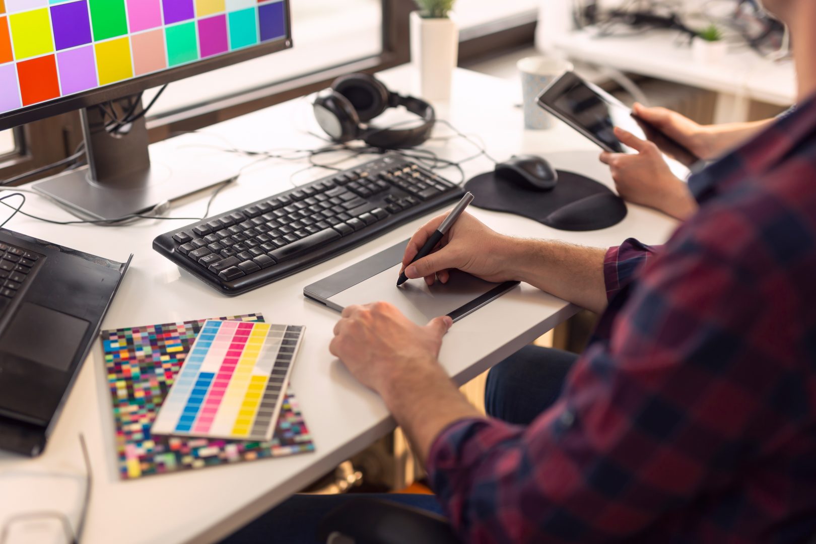A graphic designer using a drawing tool at their desk